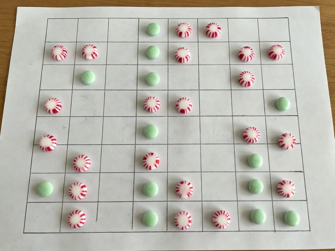 A drawn grid on paper with mint candies acting as game pieces